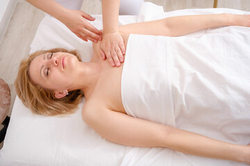 Girl lies on her back having massage from body therapist