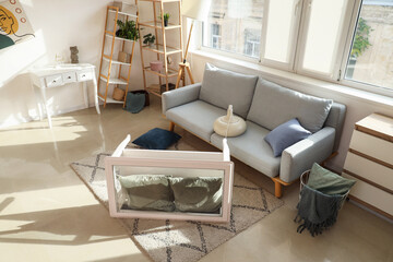 Interior of messy living room with grey sofa, overturned coffee table and shelving units after earthquake