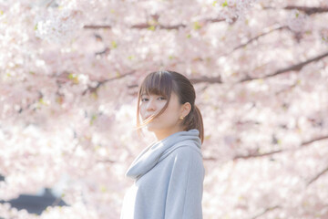 春、桜を背景に佇む女性、カメラ目線