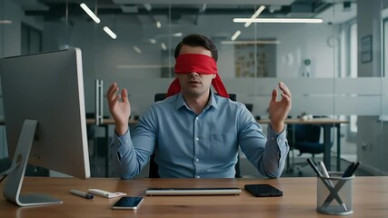 Businessman Wearing Red Blindfold Sitting At Desk With Hands Raised in Modern Office Environment With Blue Shirt