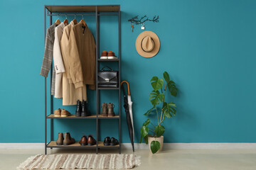 Interior of stylish hall with shelving unit, houseplant and key holder on blue wall