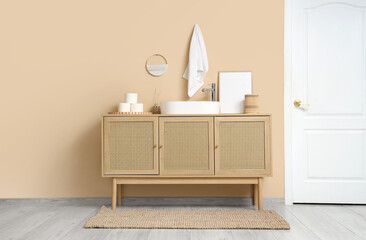 Interior of stylish bathroom with sink, wooden cabinet and white door