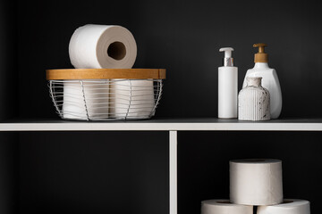 Rolls of toilet paper and bathing accessories on shelving unit, closeup
