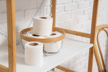 Rolls of toilet paper on shelving unit in stylish bathroom, closeup