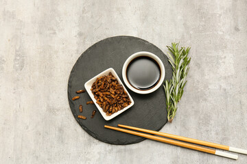 Bowl of fried insects with rosemary and soy sauce on grey background