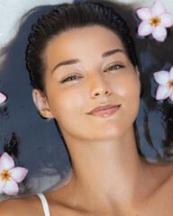 Beautiful Woman Relaxing In Water With Tropical Flowers Around Face