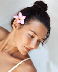 Fototapeta premium Peaceful Asian Woman With Frangipani Flower Enjoying Spa Skincare Moment