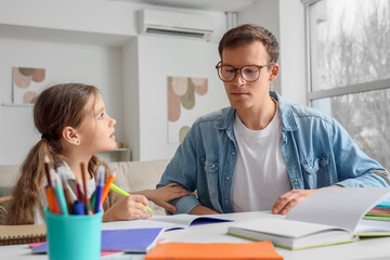 Obraz premium Teenage girl studying with tutor at table in room