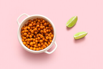 Bowl with tasty fried chickpeas and lime on pink background
