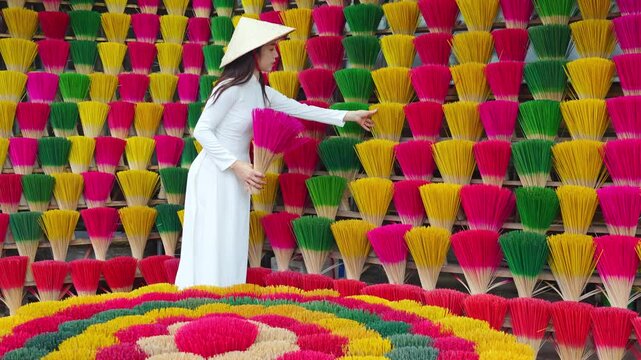 4k slow motion video, Asian woman wears traditional white Vietnamese cultural clothes with a conical hat and colorful incense sticks.