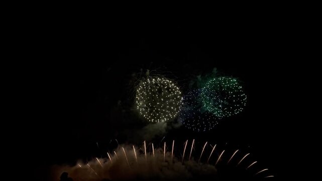 4K. loop seamless of real fireworks background golden shining fireworks with bokeh lights in the night sky. glowing fireworks show. New year's eve fireworks celebration multiple colors 
