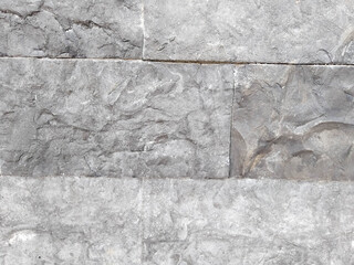 Gray natural stone surface texture on the exterior wall of a building.