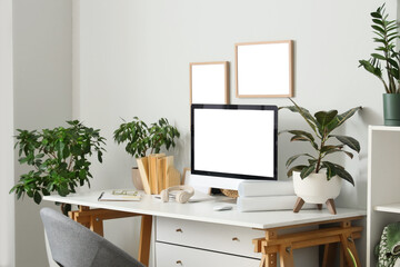 Interior of stylish home office with comfortable workspace, modern computer and houseplants