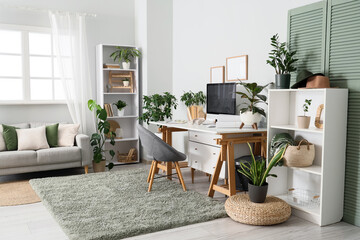 Interior of stylish home office with comfortable workspace, modern computer and houseplants