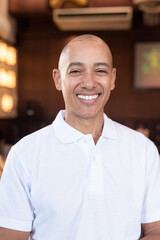 Fototapeta premium Confident Bald Hispanic face man in white polo shirt sitting in Chinese style coffee shop