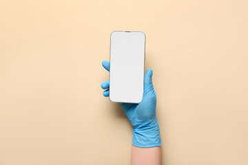Hand of doctor holding mobile phone on beige background