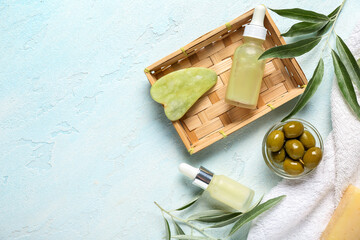 Composition with bottles of natural essential oil, guasha massage tool and green olives on light background