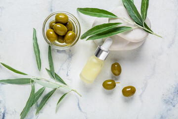 Composition with bottle of natural essential oil spa stones and green olives on light background