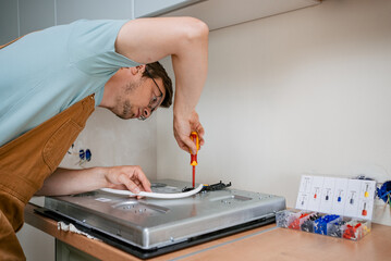 Professional electrician connecting kitchen stove wires with precision, performing electrical...
