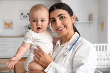 Female pediatrician holding baby in clinic, closeup
