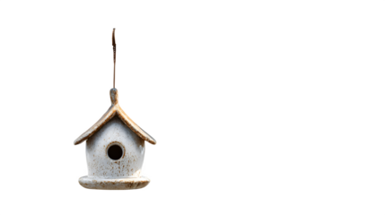 A small, decorative ceramic birdhouse hanging from a tree branch in a yard, isolated on a Transparent background
