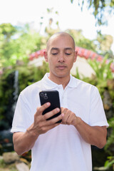 Modern man in Zen garden using smartphone, blending nature and technology