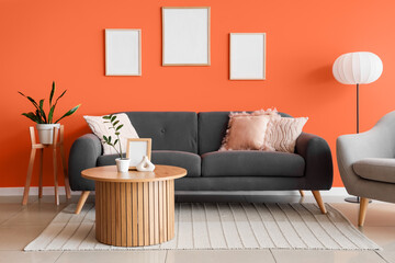 Interior of stylish living room with sofa, table and blank frames