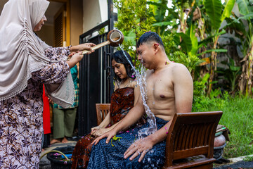 Javanese couple celebrating mitoni, traditional seven month pregnancy ritual in Indonesia