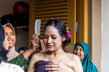 Indonesian women preparing pregnant woman for mitoni, seven month ritual