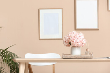 Tray with pink hydrangea flowers and reed diffuser on dining table in room
