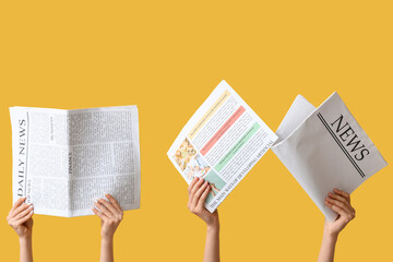 Female hands with newspapers on yellow background
