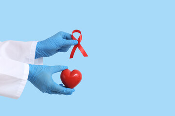 Doctor's hands with red ribbon and heart on blue background. Blood Cancer Awareness Month