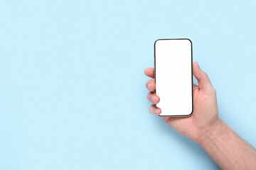 Male hand with blank mobile phone on blue background. Medicine concept