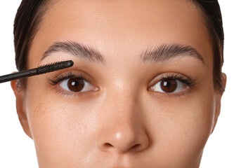 Beautiful young Asian woman applying mascara on white background, closeup