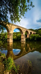 Obraz premium Stone arch bridge reflecting on tranquil water (1)