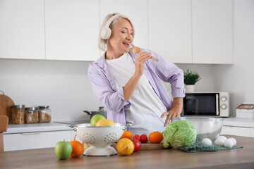 Mature woman with dancing and food o table dancing in kitchen