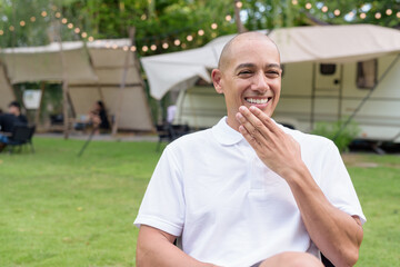 Confident bald man relaxing at campsite with camper van in outdoor travel lifestyle scene