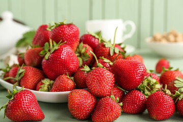 Plate with sweet ripe strawberries on green wooden background, closeup