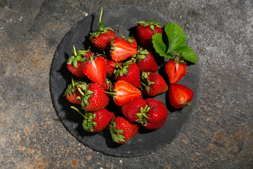 Black board with sweet ripe strawberries on dark background