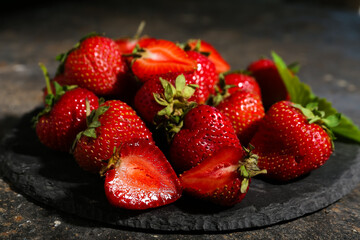 Black board with sweet ripe strawberries on dark background, closeup