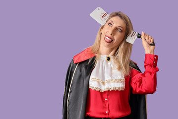 Funny mature woman dressed as vampire with axe on purple background. Halloween celebration