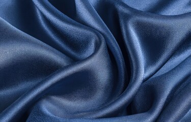 Close-up of draped, deep blue satin fabric.  Smooth, flowing folds