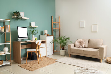 Interior of stylish living room with grey sofa, comfortable workspace, modern computer and houseplants