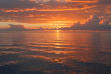 Obraz premium Golden sunset over the ocean with orange clouds and calm water surface
