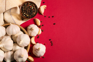 Wooden bowl with fresh garlics and peppercorns on red background