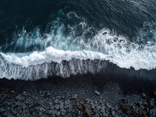 High-angle view of dark volcanic beach meeting dark ocean waves