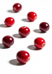 Close-up arrangement of vibrant red and dark red cranberries on a white background, showcasing their round shape and shadows.