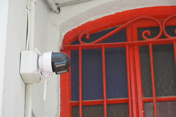 Security camera mounted on a building near a red window