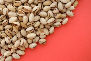 Tasty unpeeled pistachios on bright red background, top view flat lay background pattern