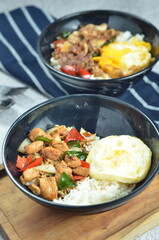 Ricebowl with egg and chicken filet served in bowl on the table